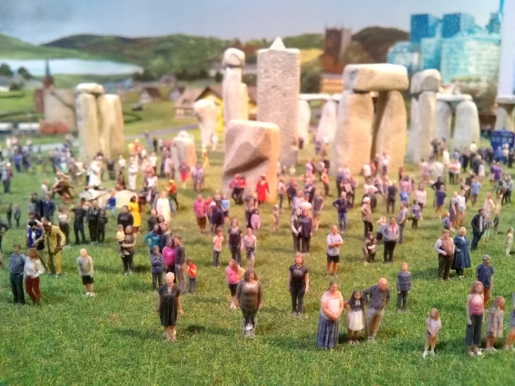 Miniature people stand in front of Stonehenge